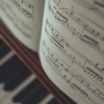 Open sheet music resting above the blurred keys of a piano