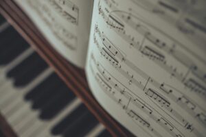 Open sheet music resting above the blurred keys of a piano