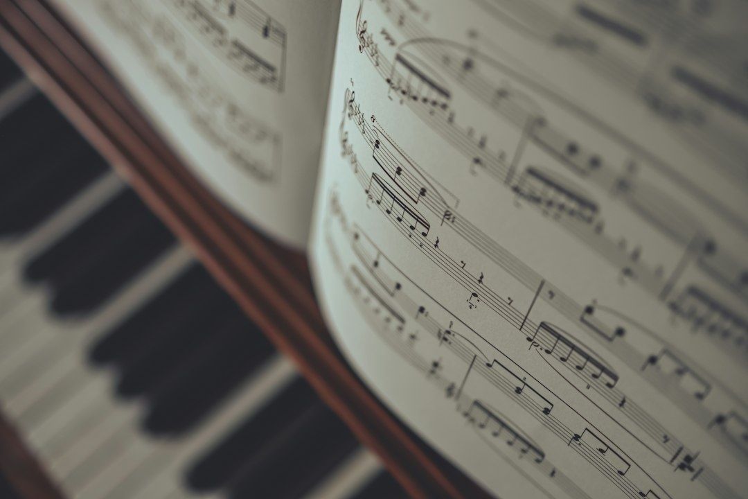 Open sheet music resting above the blurred keys of a piano