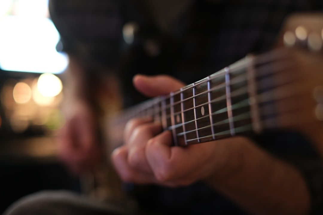 Close-up of hands forming chords on an acoustic guitar fretboard